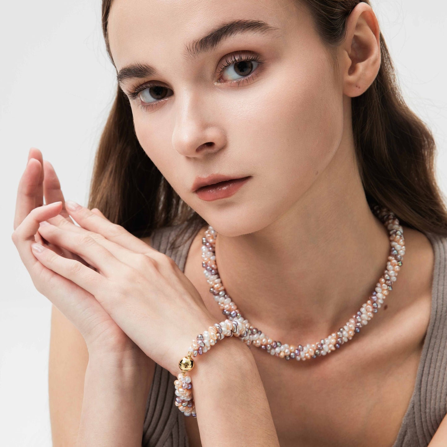 Woman wearing gold plated pearl necklace and bracelet on a white background