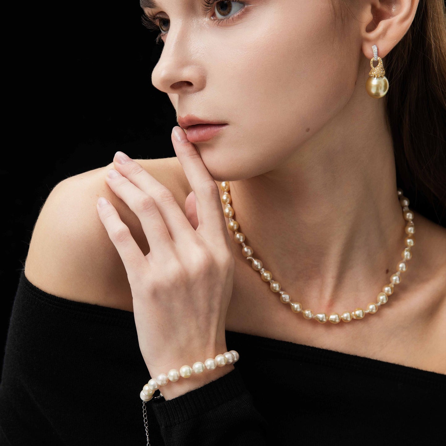 Woman wearing pearl necklace and bracelet with a black background