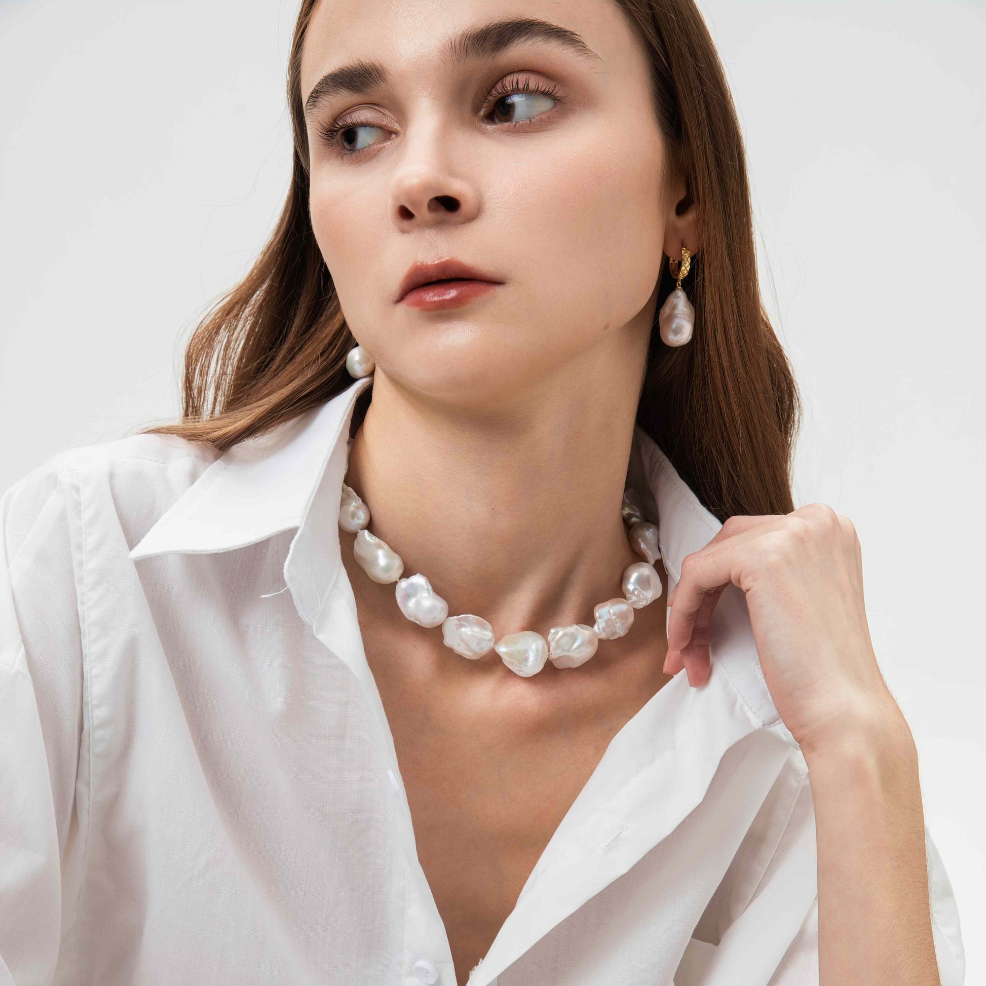 Woman wearing a pearl necklace and earrings on a white background