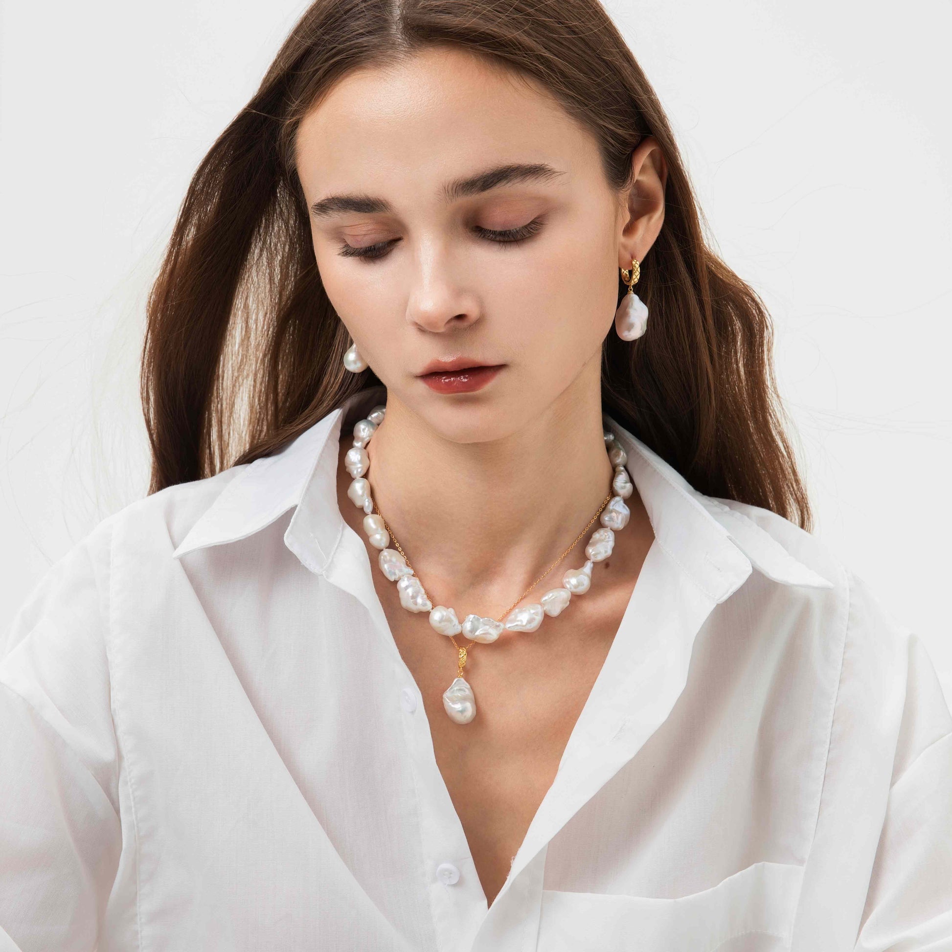 Woman wearing a pearl necklace with very high luster and earrings on a white background