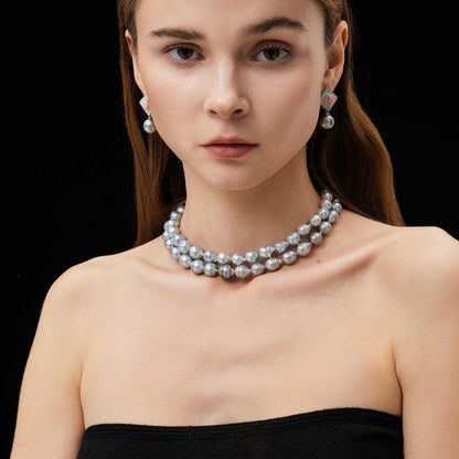 Woman wearing a pearl necklace and earrings on a black background