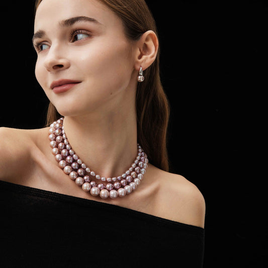 Woman wearing a pearl necklace and earrings on a black background