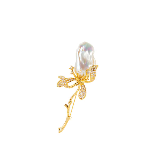 Gold brooch with a large pearl and smaller gemstones on a white background