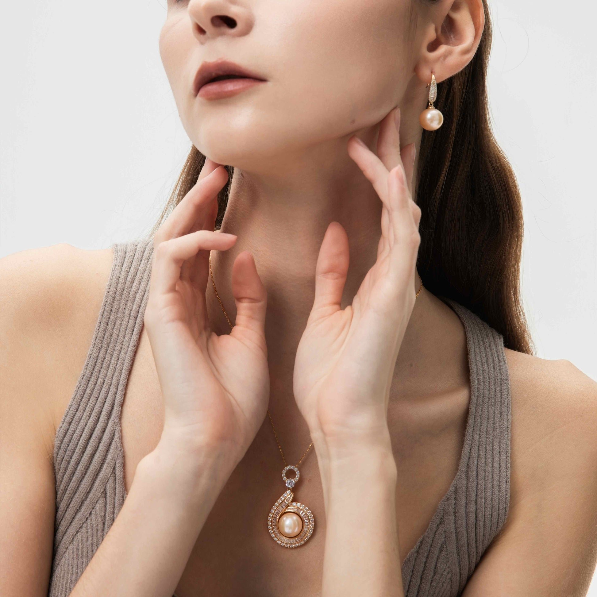 Woman wearing a pearl earring and necklace on a plain background