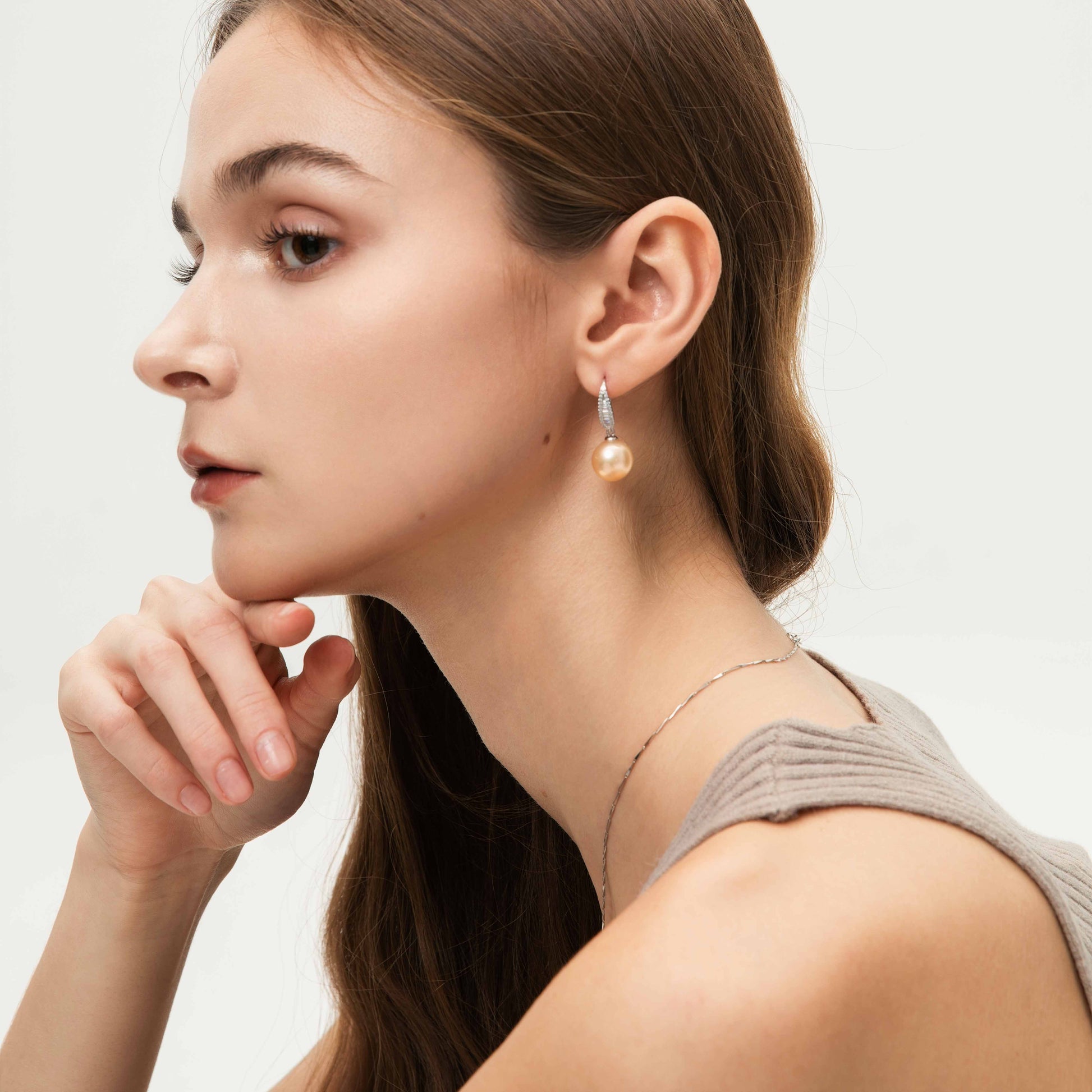 Woman wearing pearl earrings with a neutral background