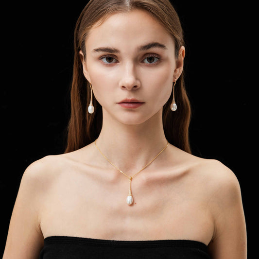 Woman wearing a gold necklace and earrings on a black background