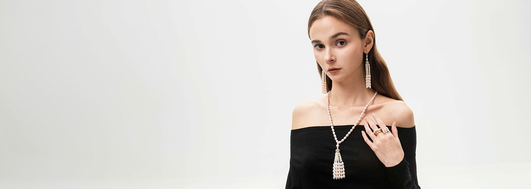 A woman with long hair wearing pearl necklace and earrings.